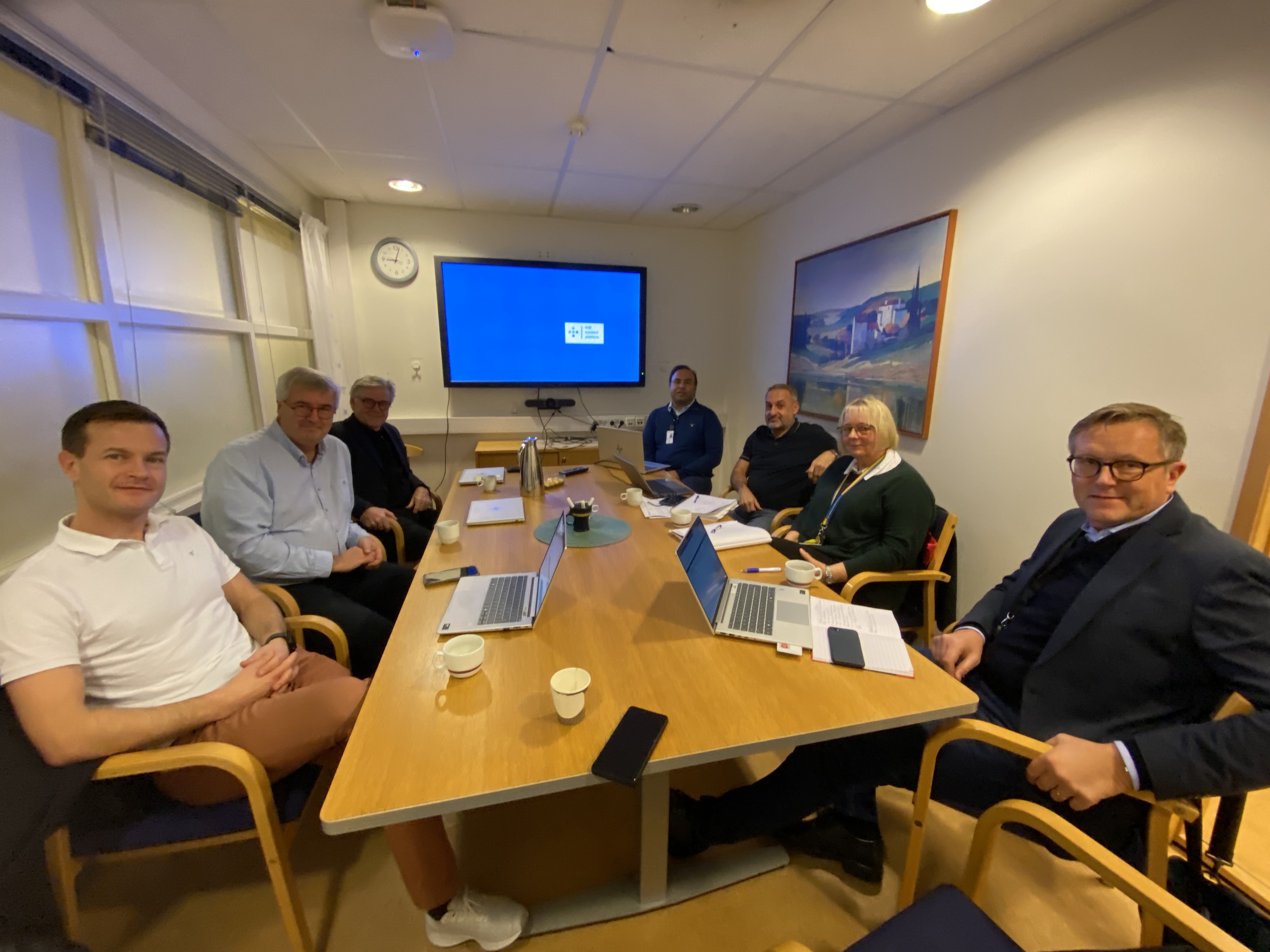 A group of people sitting around a table with laptops