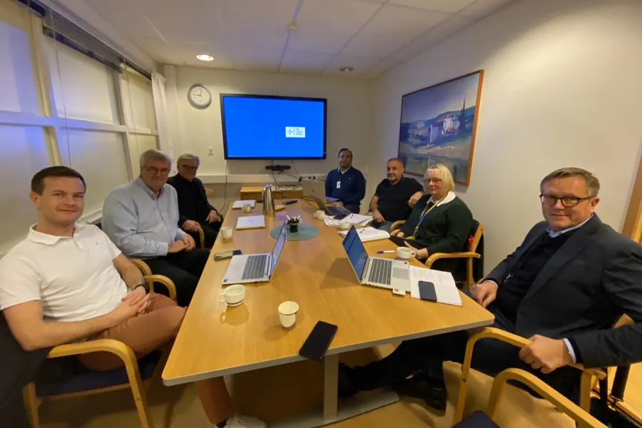 A group of people sitting around a table with laptops