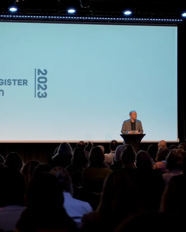 En person på en scene med en folkemengde som ser på