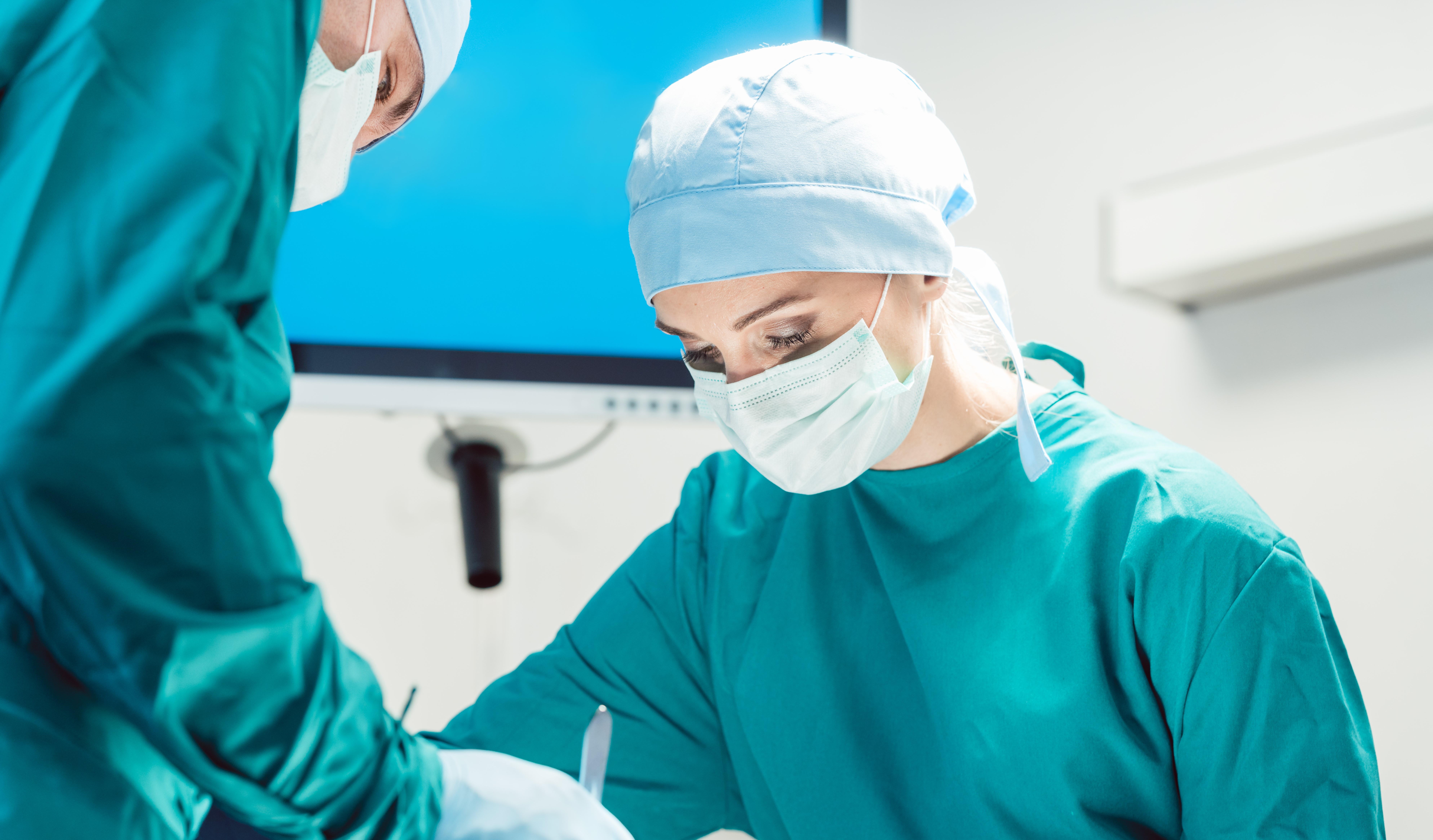 Two persons dressed in green clothes performing surgery