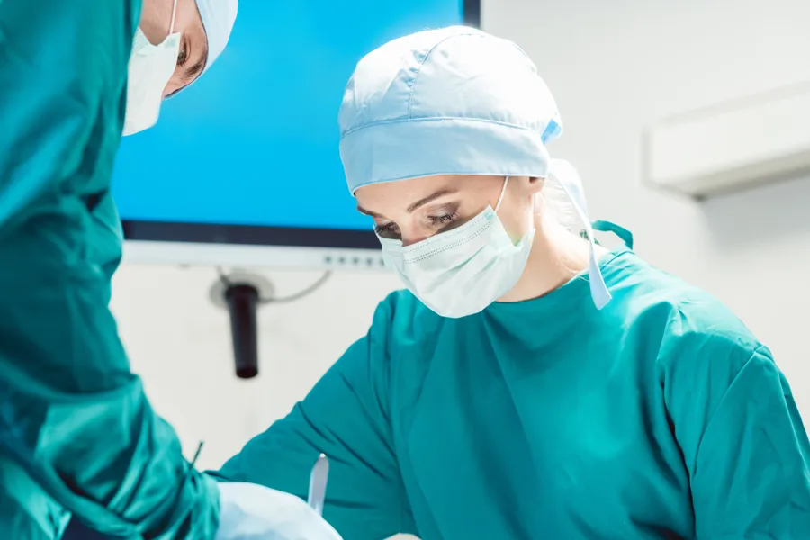 Two persons dressed in green clothes performing surgery