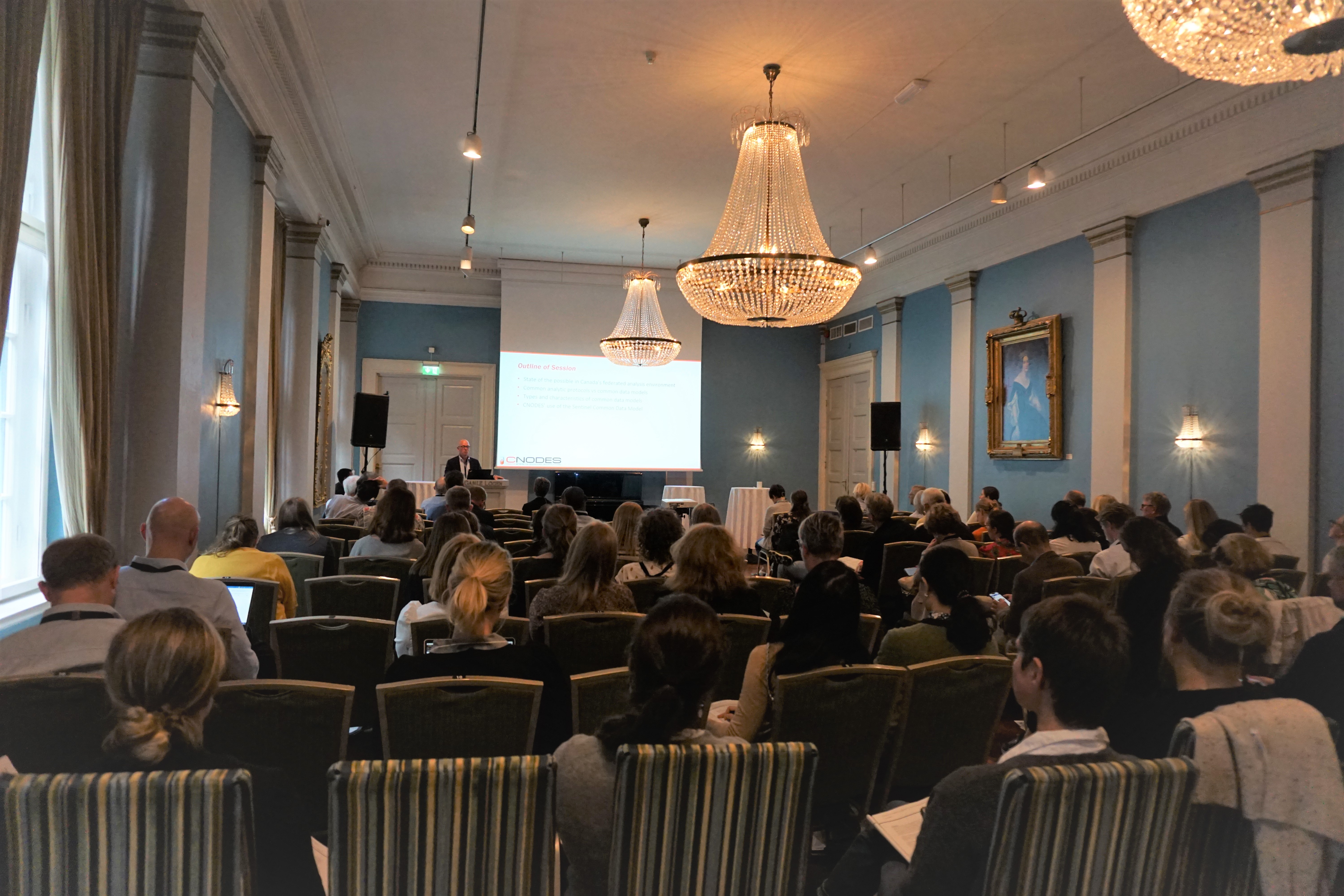 A group of people sitting in a room with a large screen