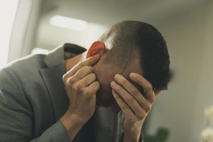 Mann holder seg for hodet