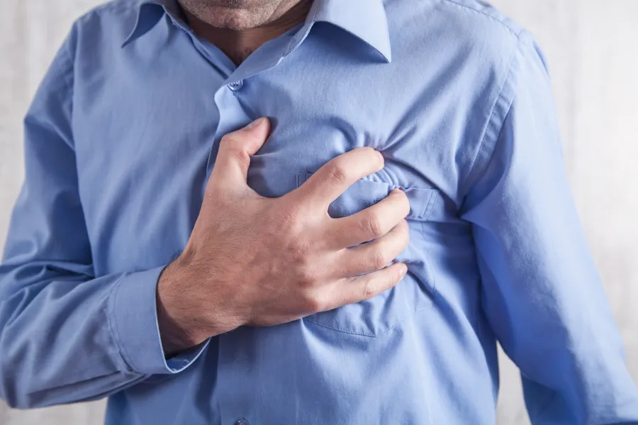 En mann holder seg på brystet