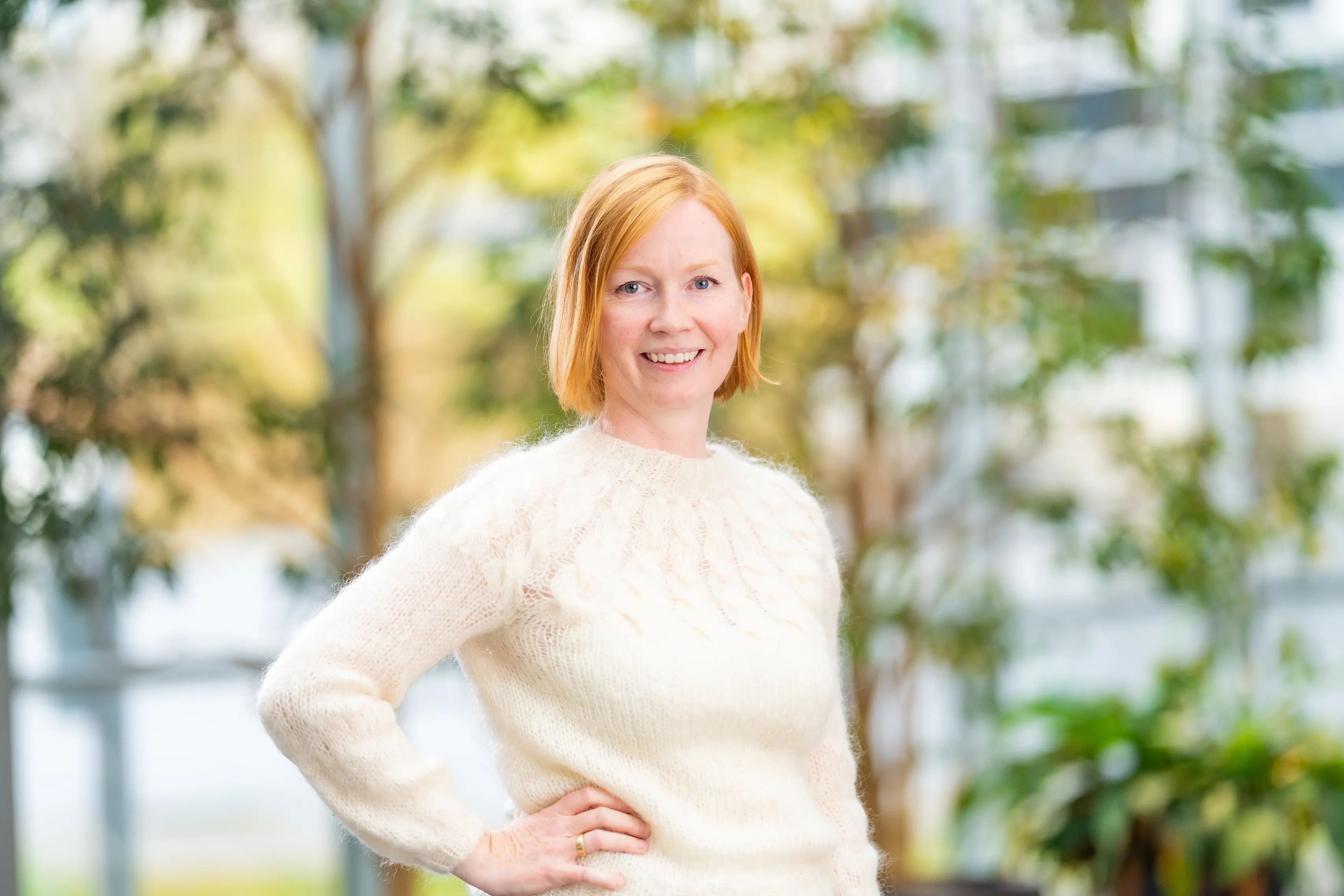 A woman standin in front of some trees