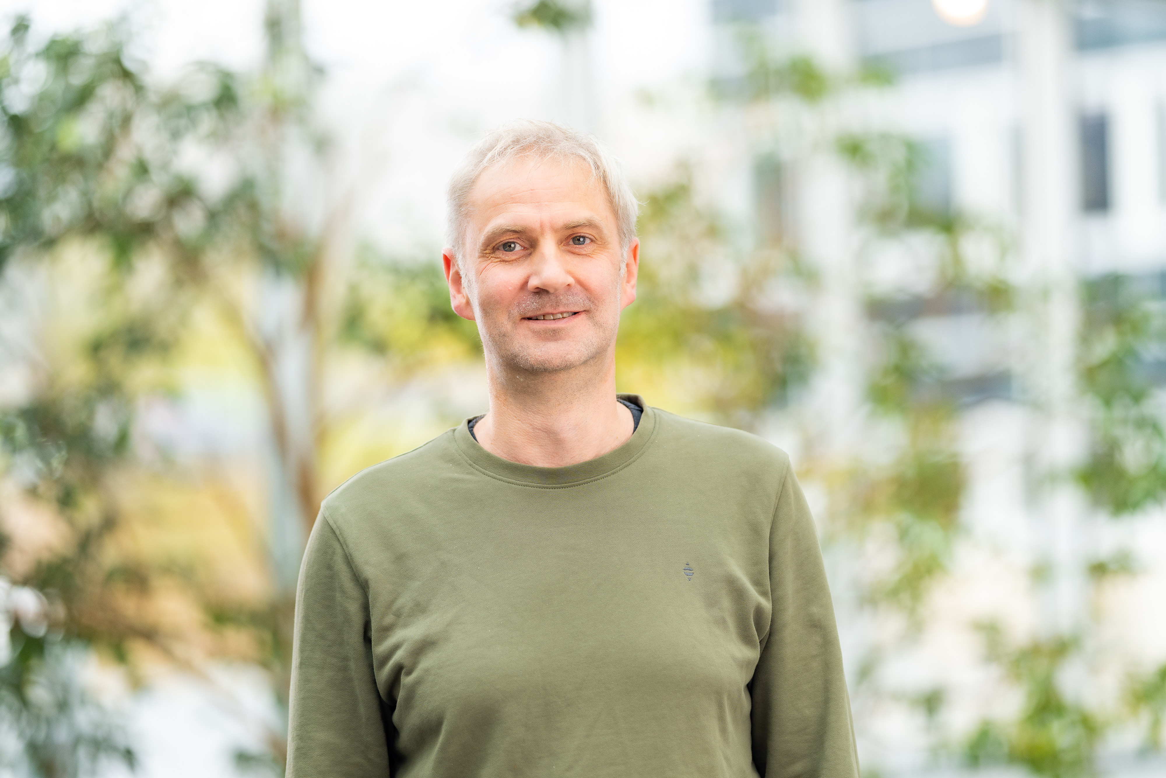 A man standing in front of green plants