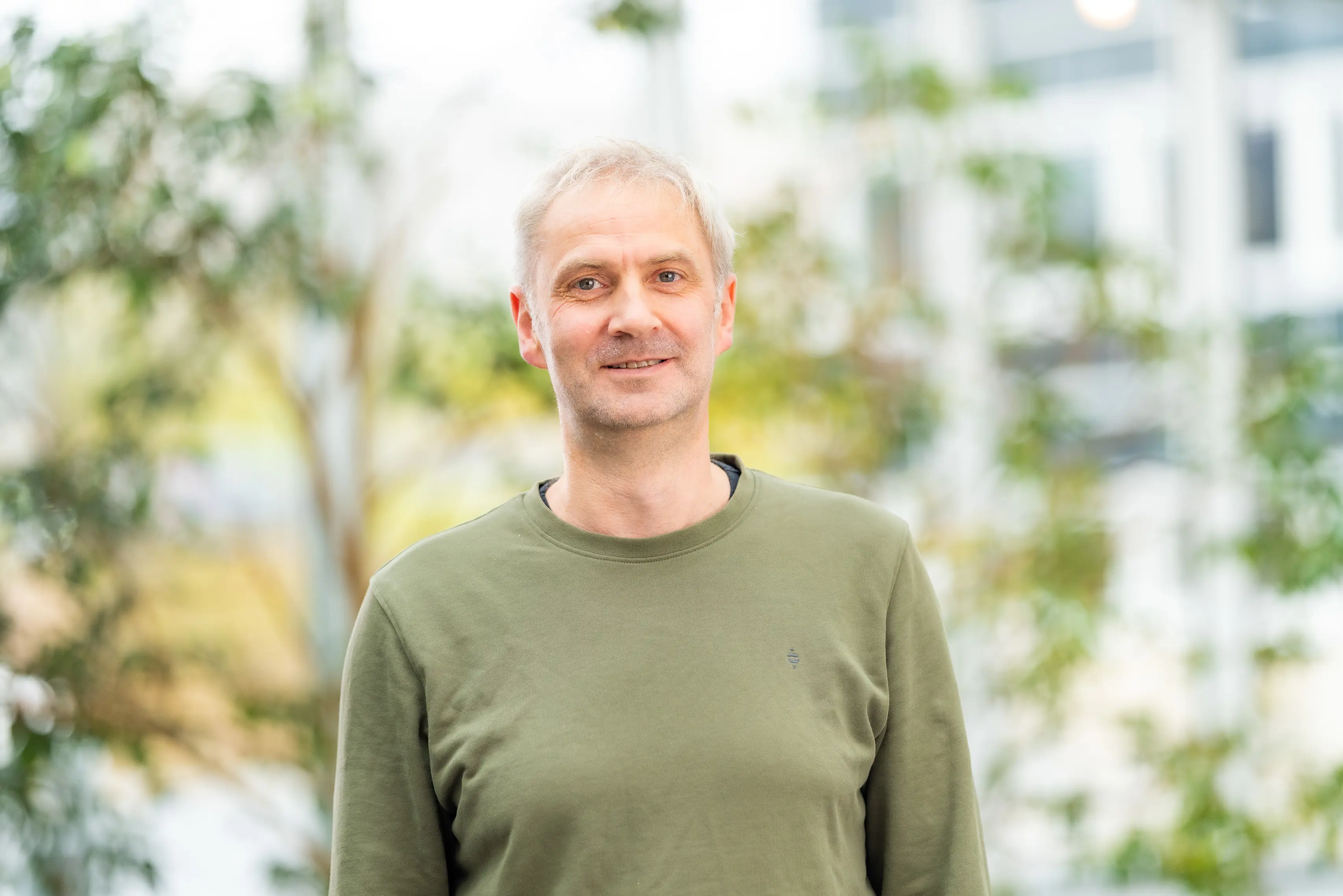 A man standing in front of green plants