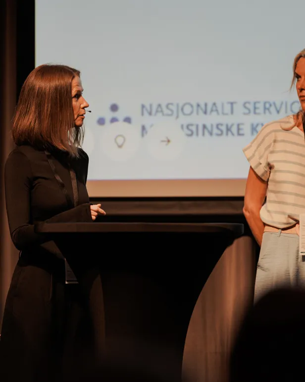 En kvinne som står ved siden av en kvinne som sitter ved et piano