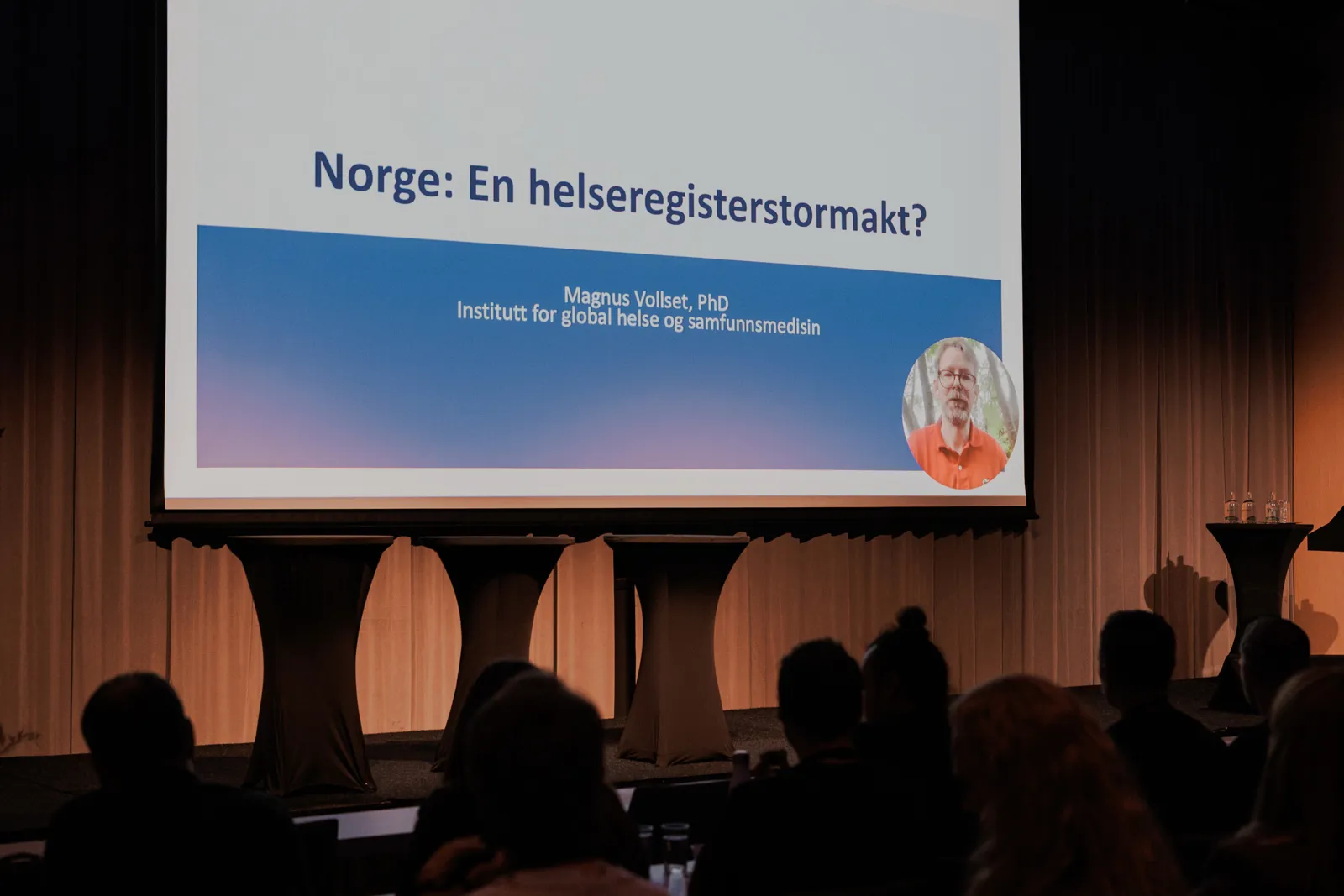En gruppe mennesker foran en stor skjerm