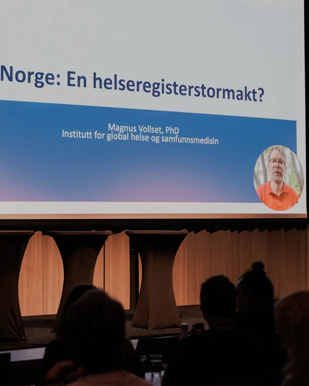 En gruppe mennesker foran en stor skjerm