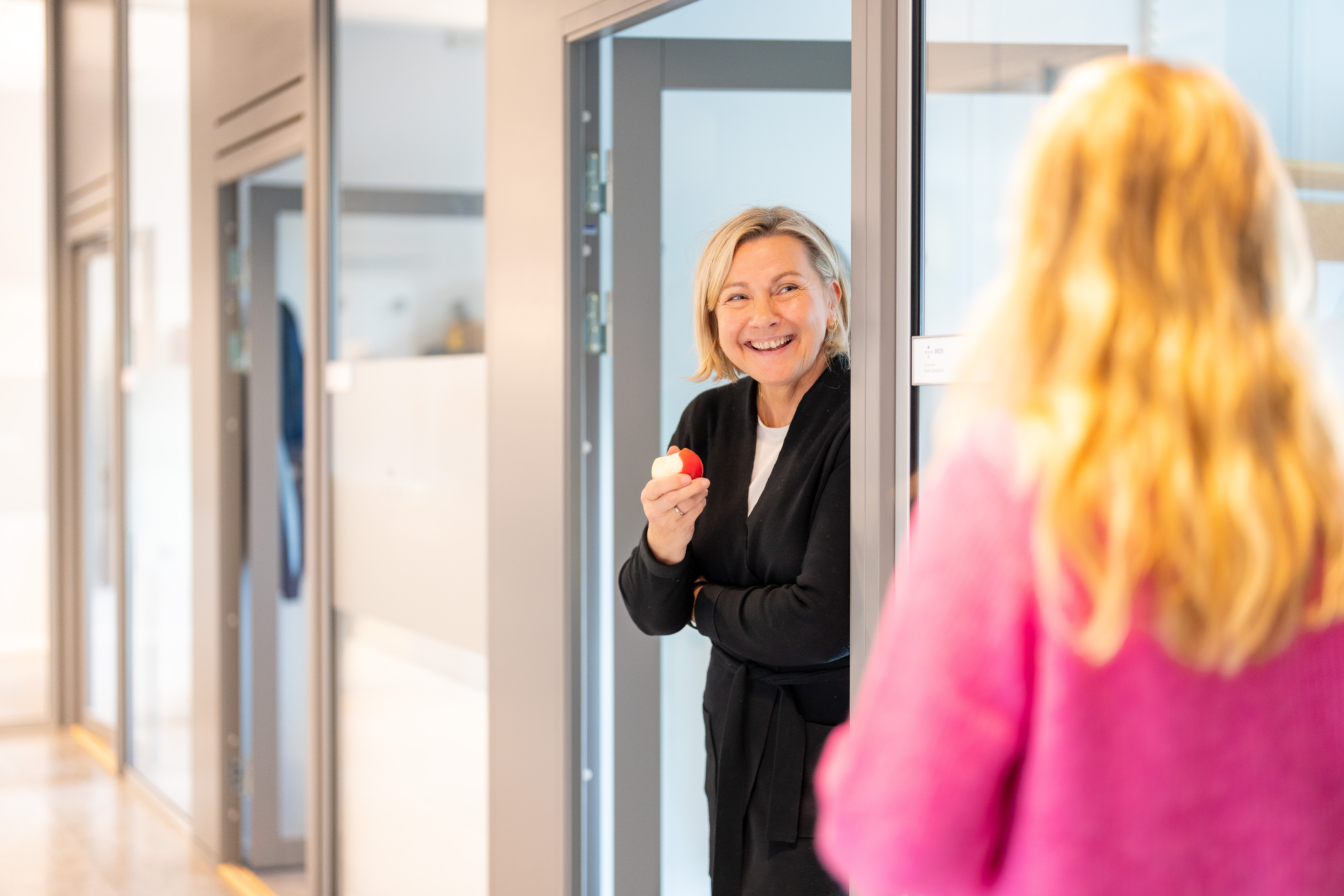 A woman in a suit smiling in a hallway