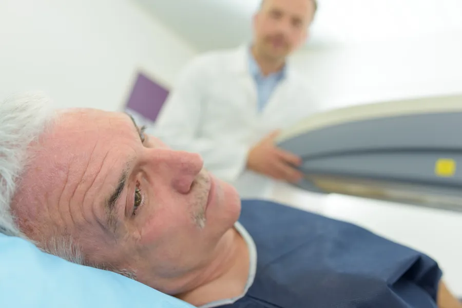 Elderly man in a hospital bed with a healthcare worker beside him